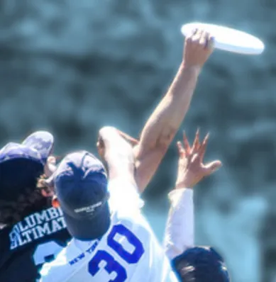 A player from Uptown Local, Columbia's Ultimate Frisbee Team, outmaneuvers two competing players to successfully catch a frisbee in mid-air.